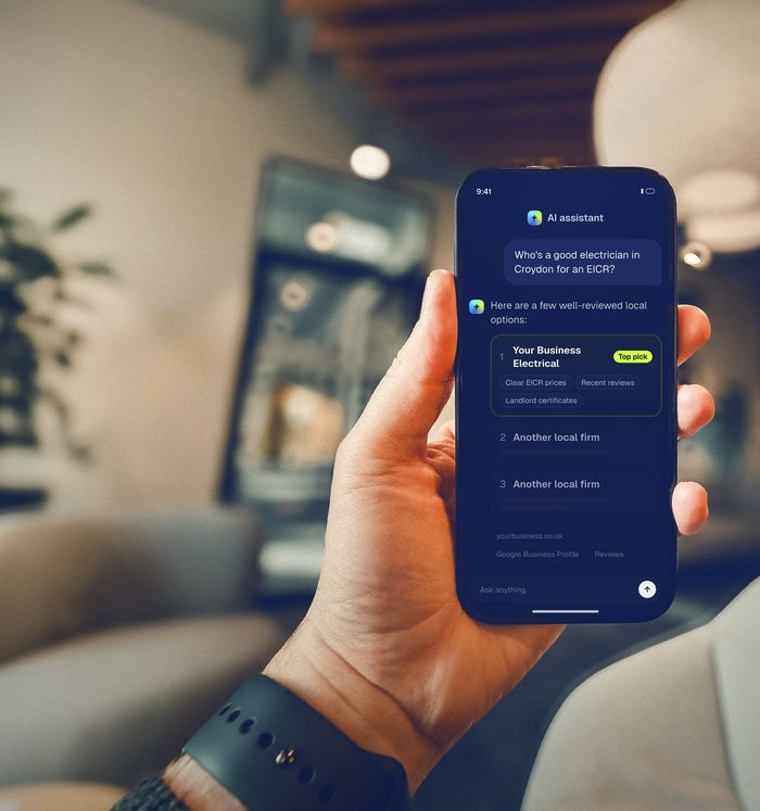Hand holding a phone showing an AI assistant recommending a local electrician (illustration)